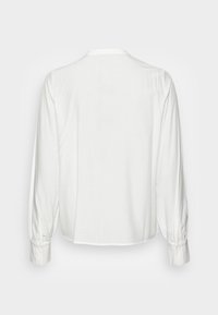 Camicia bianca a maniche lunghe vista da dietro, con polsini abbottonati e un semplice scollo tondo.