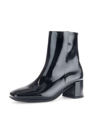 Botte de cheville en vernis noir, avec un bout pointu, un talon block et une texture lisse et brillante. Elle présente des coutures minimales et un design épuré.