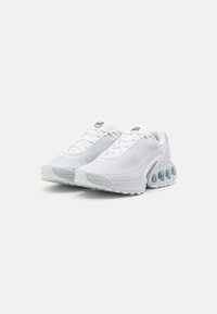 Witte sportieve schoenen met een bovenwerk van mesh, een textuurdesign, een ronde neus en zichtbare dempingsbellen op de hak. Veters en logo-details zijn aanwezig.