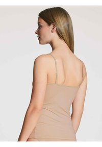Beige top met dunne schouderbandjes, gladde textuur, aansluitend ontwerp en verstelbare bandjes, gezien vanaf de zijkant.