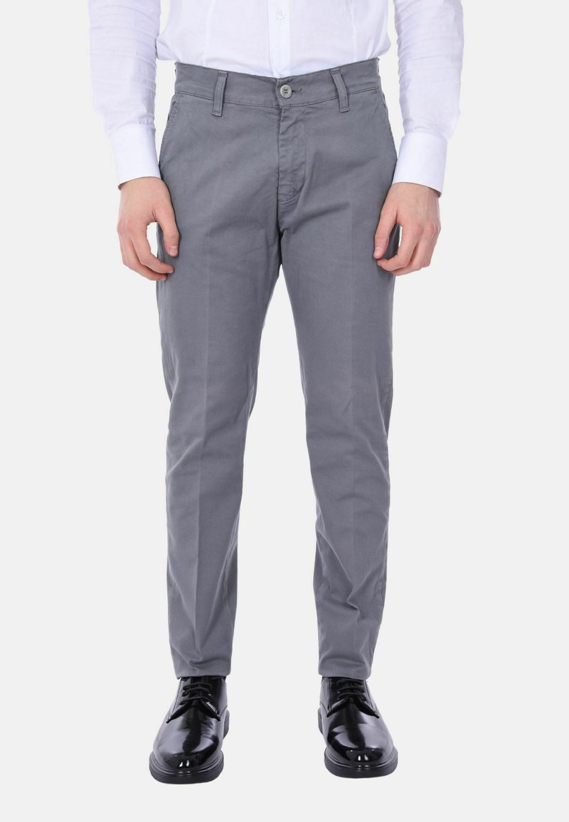 Chinos in cotone grigi con vestibilità slim, dotati di chiusura a bottone, tasche laterali e una texture liscia, abbinati a scarpe nere lucide.
