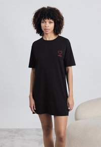 Μαύρο κοντομάνικο φόρεμα από βαμβάκι, με σχέδιο κόκκινης καρδιάς και λογότυπο "HUGO" στο στήθος. Απλή, χαλαρή εφαρμογή.