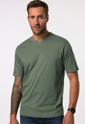 Grünes Kurzarm-V-Ausschnitt-T-Shirt aus weichem Stoff. Es hat einen lockeren Schnitt und eine glatte Textur und wird mit dunklen Jeans und einer schwarzen Uhr kombiniert.