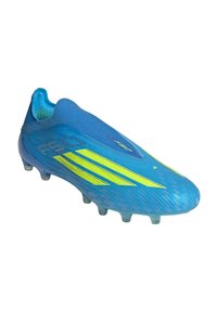 Chaussure de football bleue avec des bandes jaunes fluo, design sans lacets et crampons sur la semelle pour jeu sur terrain ferme.