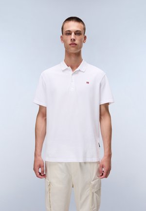 Hvid polo-shirt med en tre-knaps lukning, korte ærmer og et lille rød og blåt logo på brystet, parret med lysebeige cargo-bukser.