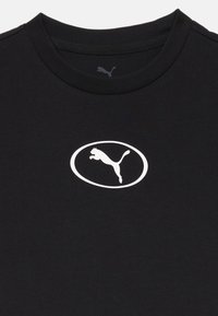 Μαύρο βαμβακερό μπλούζα με λευκό οβάλ λογότυπο που απεικονίζει έναν πούμα που πηδά. Απλός σχεδιασμός με στρογγυλή λαιμόκοψη, κοντά μανίκια και λεία υφή.