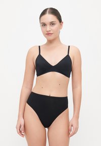 Black seamless bralette with adjustable straps, V-neck design. Paired with high-waisted black bikini bottoms, both made of smooth fabric.