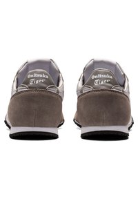 Šedé nubukové a syntetické tenisky s bílými akcenty a gumovými podrážkami. Vybavené značkovými patními tabulkami a elegantním, zaobleným tvarem.