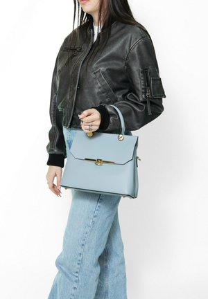 Light blue structured handbag with a top handle, gold hardware, and a folding flap closure. Smooth texture and rectangular shape.