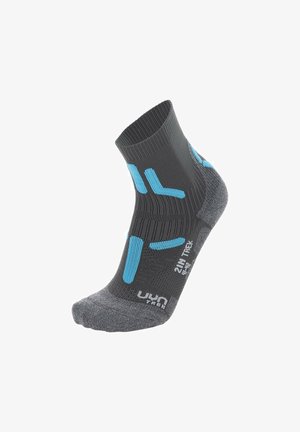 Grijze sport sok gemaakt van zacht materiaal, met blauwe accenten en een ribbelontwerp met textuurgebieden voor grip en ondersteuning.