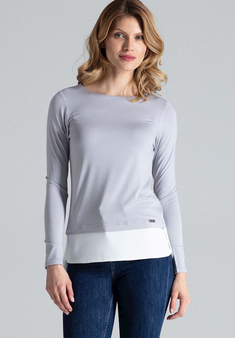 Grijze longsleeve top met een aansluitend ontwerp, gemaakt van gladde stof. Gelaagd met een witte zoom aan de onderkant. Gedragen met donkerblauwe jeans.