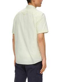 Lichtgele shirt met korte mouwen van een gladde stof, voorzien van een standaard kraag en een horizontale achterkant met een lus.