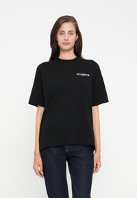 T-shirt in cotone nero con vestibilità rilassata, maniche corte e scollatura a girocollo, che presenta un logo bianco "ALLSAINTS" sul lato sinistro del petto.