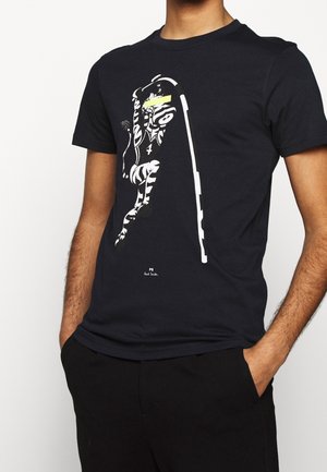 T-shirt en coton bleu marine avec un imprimé graphique représentant une figure stylisée en blanc et jaune, manches courtes, col rond et coupe décontractée.
