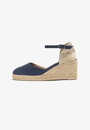 Chaussure espadrille compensée avec tige en tissu bleu marine, bride à la cheville avec boucle, talon beige tressé et semelle plateau en jute tressé.