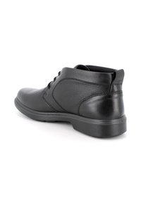 Scarpa nera in pelle con lacci a basso profilo, angolata per mostrare il lato esterno e il tallone, con suola texturizzata su sfondo bianco.