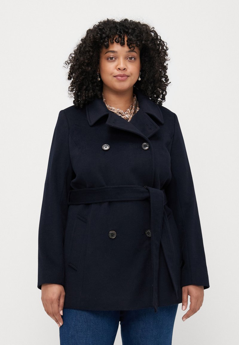 Marineblauer Peacoat mit doppelreihigen Knöpfen, weitem Kragen, Seitentaschen und einem Stoffgürtel, der eine glatte Textur und klassisches Design aufweist.