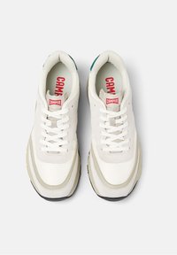 Paire de baskets blanches à lacets avec des accents beiges et le logo Camper sur la languette et la semelle intérieure, vues de dessus sur un fond blanc.