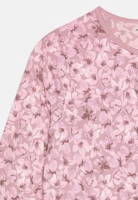 T-shirt �à manches longues en tissu doux et extensible, présentant un motif floral dans différentes nuances de rose et de mauve clair. Encolure ronde et finition texturée.