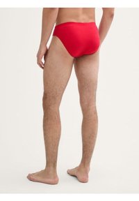 Culotte en coton rouge avec une texture lisse, un design minimaliste et une découpe haute au niveau des jambes, offrant un ajustement confortable à l'arrière.