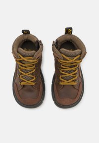 Brązowe skórzane buty trekkingowe z żółtymi sznurówkami, wyściełanym kołnierzem, siateczkową podszewką i teksturowaną gumową podeszwą. Boczne pętle ułatwiają zakładanie.