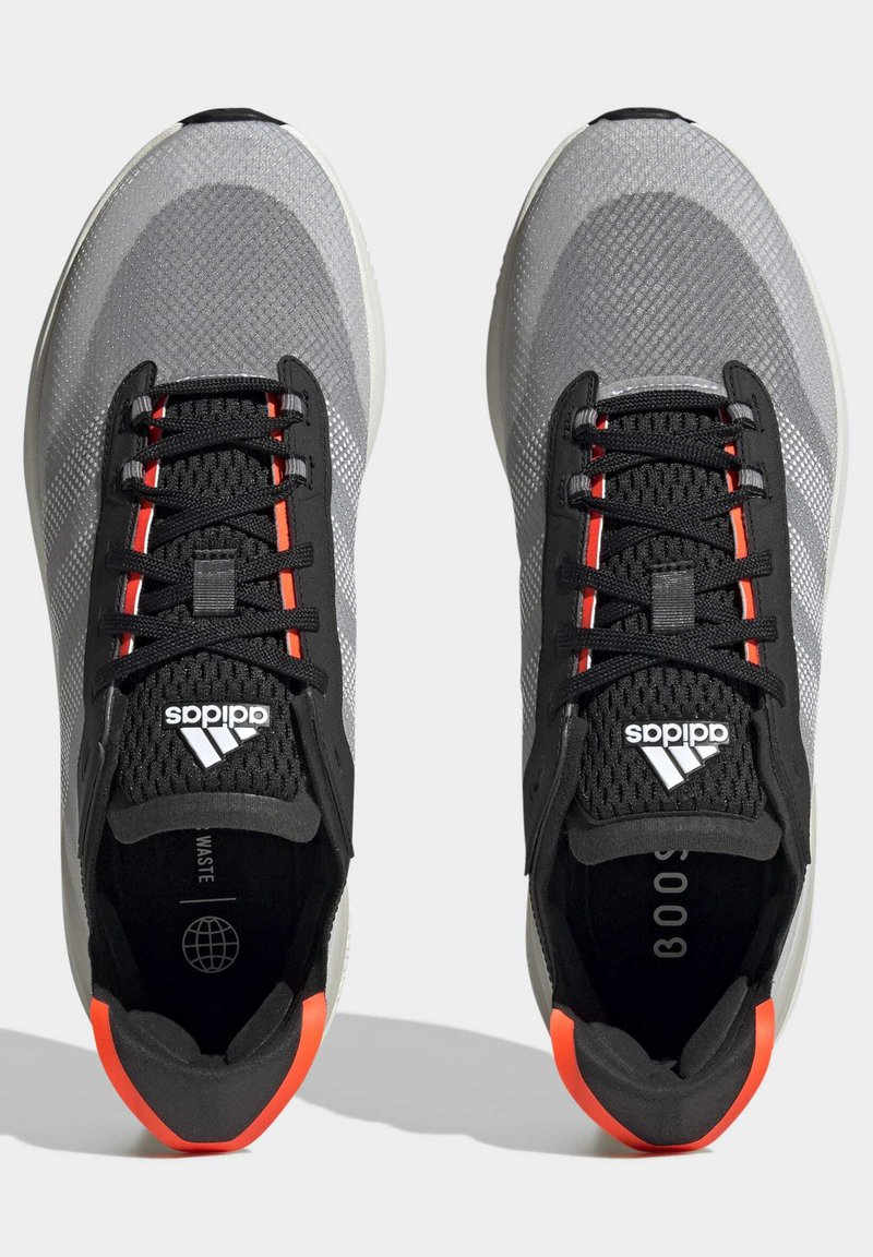 Graue Sportschuhe mit einem atmungsaktiven Mesh-Obermaterial, schwarzen Schnürsenkeln, orangen Akzenten und einer strukturierten Sohle. Mit einem Logo auf der Zunge.