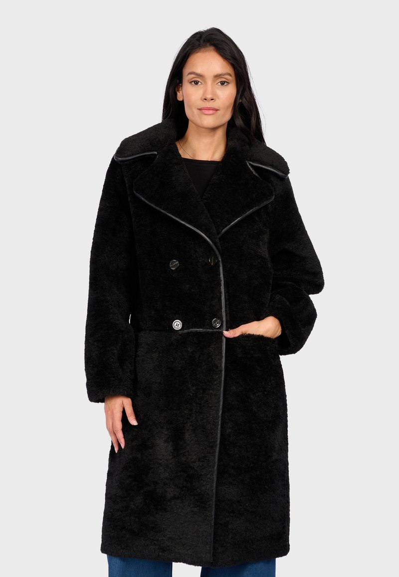 Cappotto nero e peloso con un design doppiopetto, ampio colletto e rifiniture a contrasto. Presenta grandi bottoni e tasche laterali.