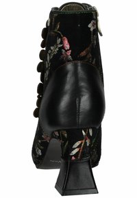 Botín de tobillo de terciopelo negro con bordado floral, tacón de cuero, detalles de botones y diseño de tacón cuadrado. Presenta un contraste de costuras en verde.