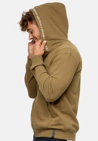 Oliven grøn hætte sweatshirt lavet af blødt stof, med ribkantede manchetter, snoretræk i hætten og logo detaljer nær kanten. Casual fit.