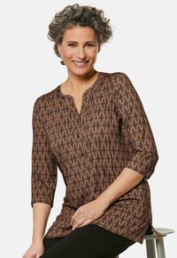 Braun gemusterte Bluse mit rundem Halsausschnitt, Dreiviertelärmeln und Knopfdetails. Verfügt über geometrische Designs und eine lockere Passform.