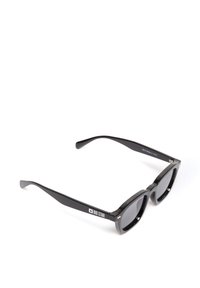 Mustad mustanvärviline päikeseprillide rätsik, millel on paksud plastraamid, tume lääts ja peene brändingu temple. Sile tekstuur ja läikiv viimistlus.