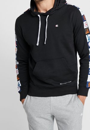 Sweat à capuche noir avec poche avant, cordons blancs et patchs de logo colorés le long des manches. Matière en mélange de coton, coupe décontractée.