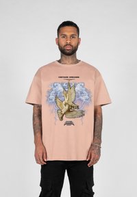 Kortermet, lyserød t-shirt i bomuld med et grafisk motiv af to duer mod en blå baggrund, med teksten "VINTAGE DREAMS."