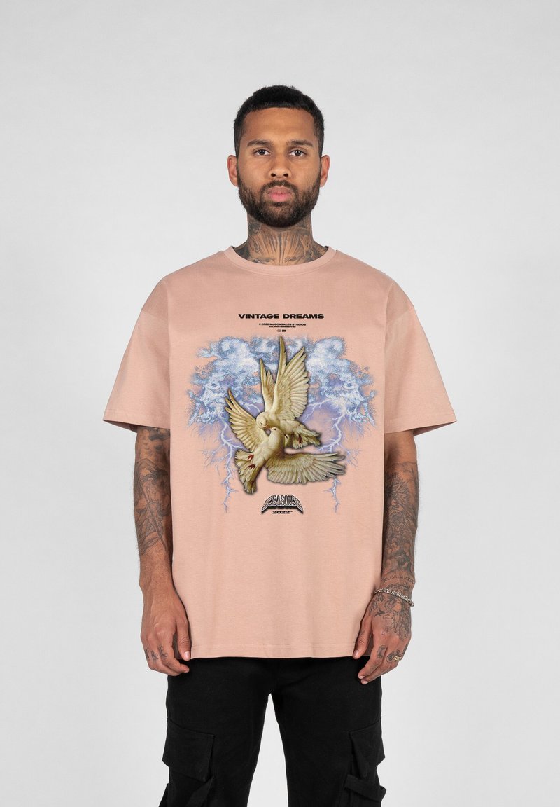 Kortermet, lyserød t-shirt i bomuld med et grafisk motiv af to duer mod en blå baggrund, med teksten "VINTAGE DREAMS."