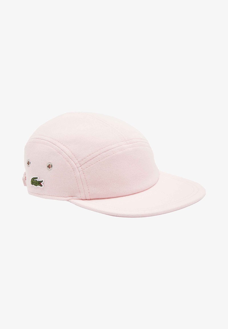Gorra rosa hecha de tela texturizada con un visera curva. Presenta un logo de cocodrilo verde bordado en el costado y agujeros de ventilación.