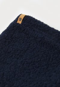 Scaldacollo in pile blu navy con materiale testurizzato. Presenta un piccolo etichetta in pelle tan con un logo sul bordo per un tocco di dettaglio in più.