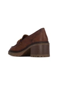 Mocasines de tacón de cuero marrón con puntera redonda, cinta decorativa y tacón de bloque texturizado. La vista lateral en ángulo muestra los detalles de costura y la suela.