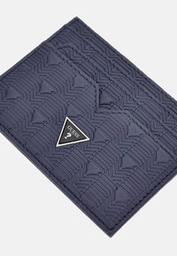 Porte-cartes bleu marine avec un motif géométrique texturé, mettant en avant un accent logo en argent triangulaire. Fabriqué en matériau synthétique.
