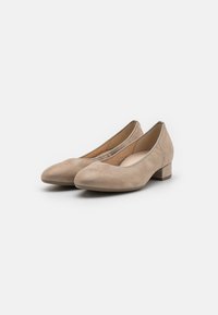 Zapatos de ante beige de tacón bajo con punta redonda, textura suave y diseño minimalista que presenta cortes laterales para mayor transpirabilidad.