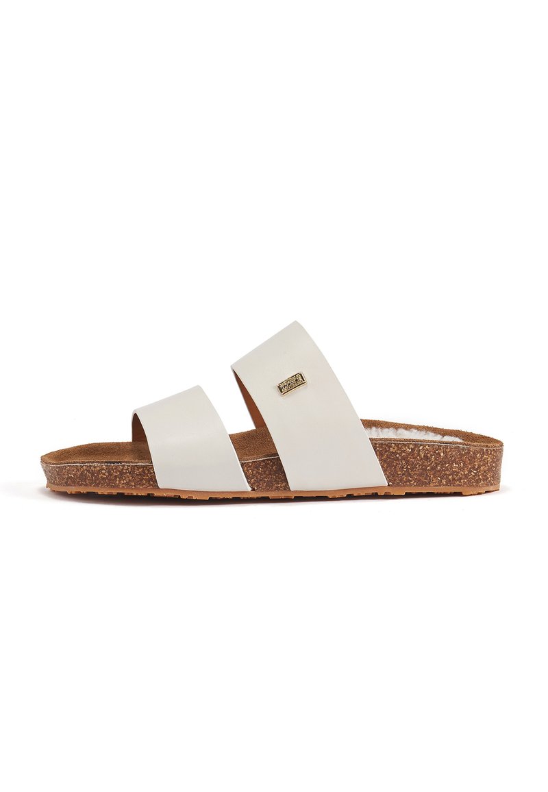 White flat slide sandals with two wide straps. Cork footbed and textured sole. Small metallic detail on the strap.