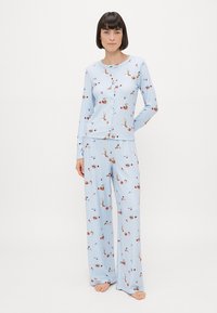 Lyseblåt pyjamas sæt med langærmet top og vide bukser, der har et blomstermønster og knaplukning foran. Blødt, ribbet tekstur.
