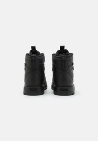 Baskets montantes noires avec une tige en cuir texturé, un col rembourré et un logo sur le talon. Elles disposent d'une semelle en caoutchouc durable.