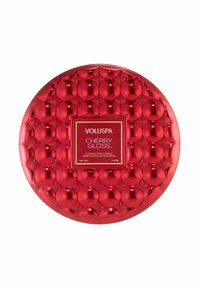 Röd rund ljusbehållare med en glansig, texturerad yta. Har en central etikett med texten "Voluspa Cherry Gloss," kokosvax, 12 oz. kapacitet.