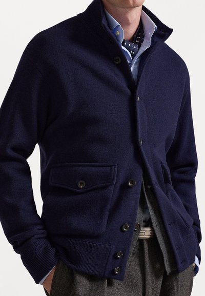 Ναυτικό κάρντιγκαν από μείγμα μάλλινου υφάσματος με ψηλό γιακά, μπροστινά κουμπιά και δύο τσέπες στο στήθος. Ριμπέτες στους καρπούς και το όριο. Σχεδιασμένο για εφαρμοστή σιλουέτα.