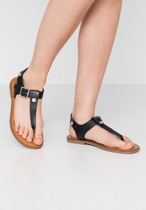 Zwarte leren teensandalen hebben verstelbare gespsluiting, een platte lichtbruine zool en een eenvoudig ontwerp waarmee de tenen goed zichtbaar zijn.