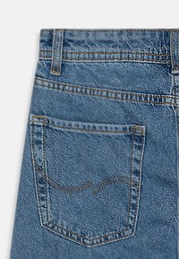 Denim jeans featuring a light blue hue, standard five-pocket design, and a back pocket with curved stitch detailing.