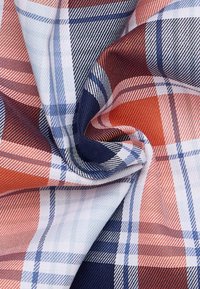 Tessuto a quadri con colori blu, rosso e bianco, caratterizzato da una trama tessuta. Il motivo include strisce che si intersecano con larghezze variabili.