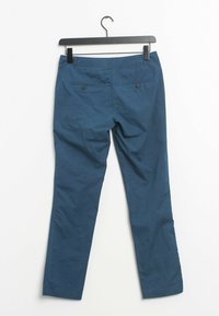 Chinos en coton bleu avec une coupe droite, dotés de deux poches arrière et de boutons en accent, suspendus à un cintre noir.