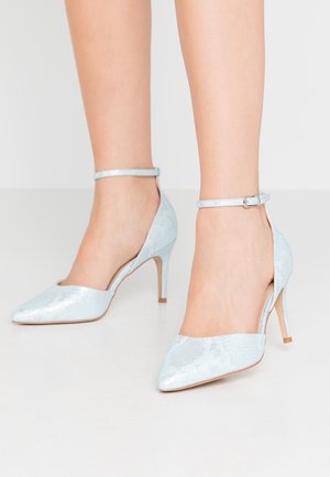 Lyseblå højhælede sko med en blank overflade, spids tå, ankelrem og skrå udskæringsdesign. Tynde, elegante hæle.