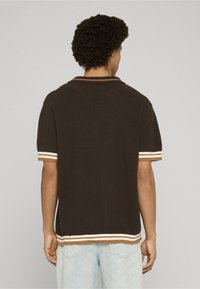 Tricou polo maro cu textură, cu mâneci scurte și guler ascuțit, având dungi crem și rugină pe mâneci și tiv.